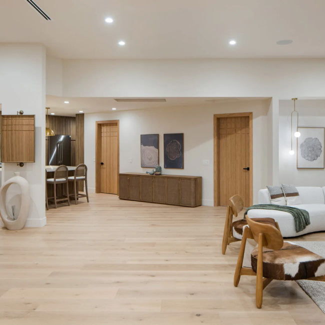 Modern living room with white sofa, wooden floor, and kitchen area.