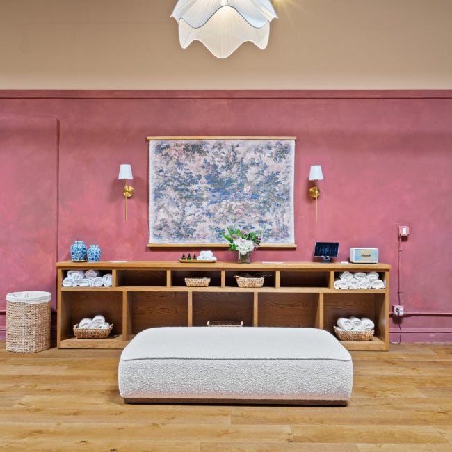 Room with pink walls, wooden floor, and shelves with various items.