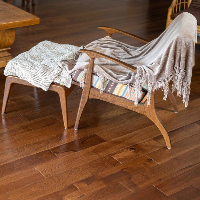 Wooden armchair and ottoman with a blanket on a wooden floor