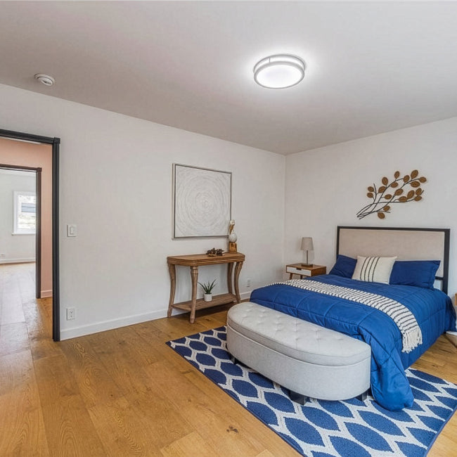Modern bedroom with blue bedding, white ottoman, and decorative elements.