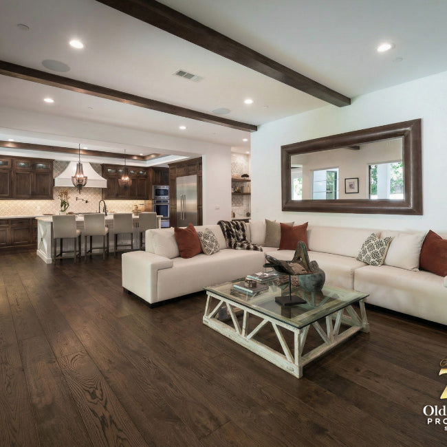 Living room with white sofa, coffee table, and kitchen in the background.