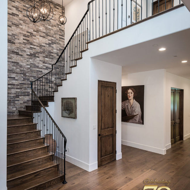 Staircase in a modern home with wooden floors and a brick wall.