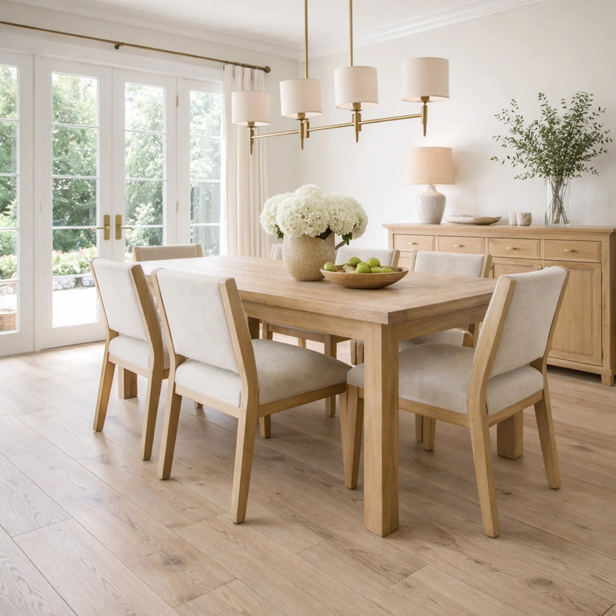 Dining room with wooden table and chairs, light fixtures, and a vase of flowers.
